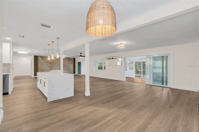 interior space featuring hanging light fixtures, light hardwood / wood-style flooring, ceiling fan, light stone countertops, and white cabinetry