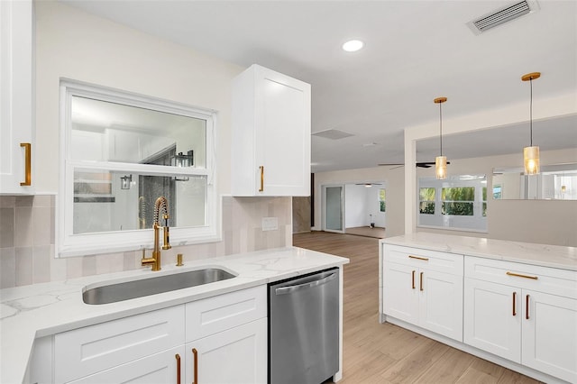 kitchen with light wood-type flooring, stainless steel dishwasher, sink, decorative light fixtures, and white cabinetry