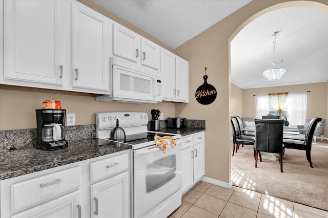 kitchen featuring light carpet, white appliances, decorative light fixtures, white cabinetry, and lofted ceiling