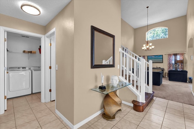 hallway with washing machine and clothes dryer, light tile patterned floors, a textured ceiling, and a chandelier