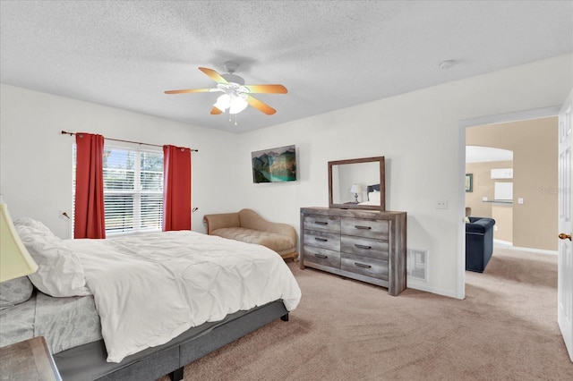 bedroom featuring a textured ceiling, light colored carpet, and ceiling fan