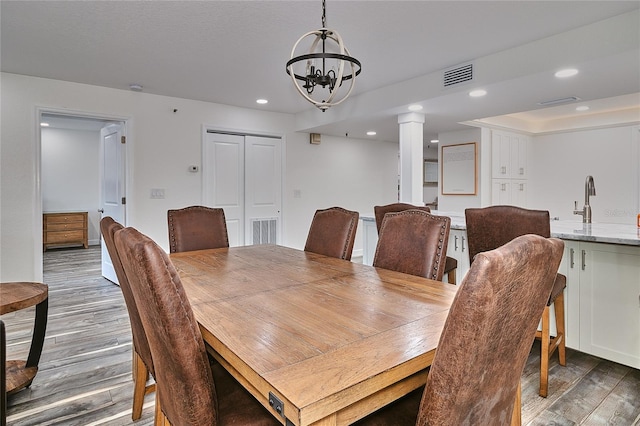 dining area with ornate columns, sink, dark hardwood / wood-style floors, and a notable chandelier