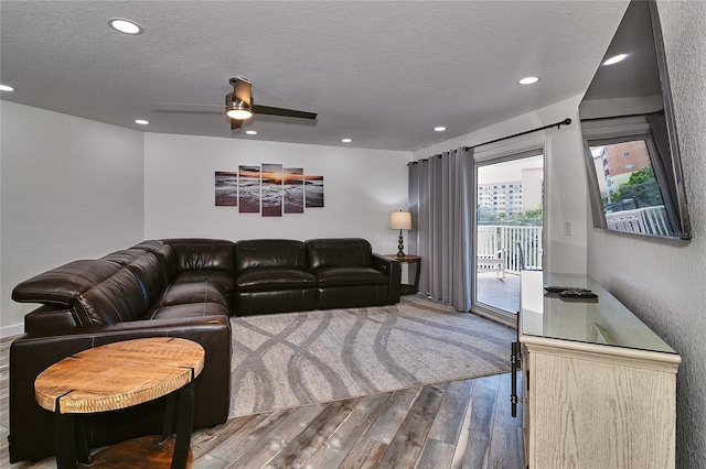 living room with hardwood / wood-style flooring, ceiling fan, and a textured ceiling