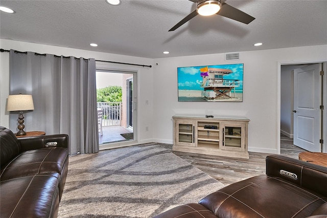 living room featuring ceiling fan, wood-type flooring, and a textured ceiling