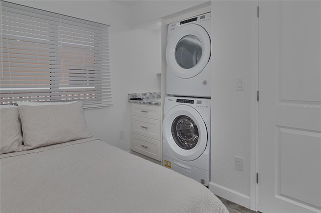 bedroom featuring hardwood / wood-style floors and stacked washer / drying machine