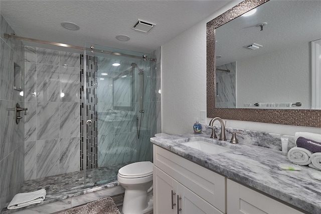 bathroom with vanity, a shower with shower door, a textured ceiling, and toilet