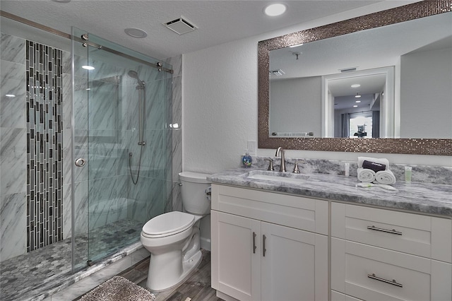 bathroom with an enclosed shower, vanity, a textured ceiling, hardwood / wood-style floors, and toilet