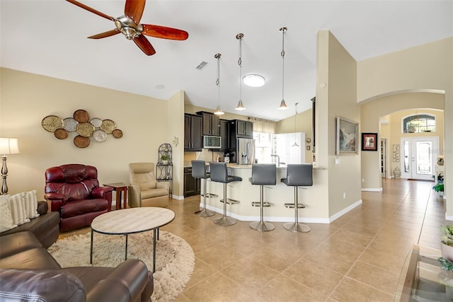 tiled living room with ceiling fan, a healthy amount of sunlight, high vaulted ceiling, and french doors