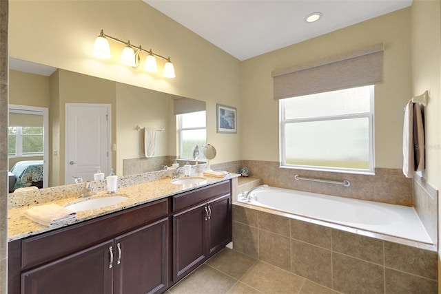 bathroom featuring tile patterned floors, vanity, a healthy amount of sunlight, and a relaxing tiled tub