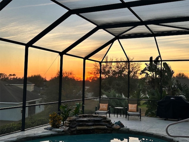 pool at dusk featuring a patio, glass enclosure, and a grill