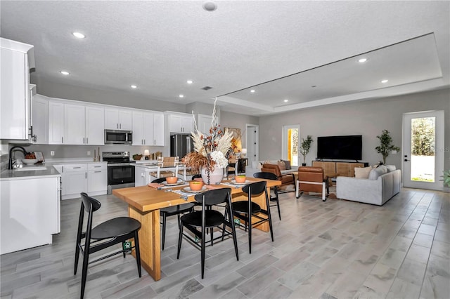 dining space featuring a tray ceiling, a textured ceiling, and recessed lighting