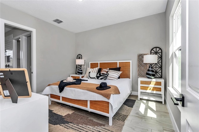 bedroom featuring light wood finished floors, multiple windows, visible vents, and baseboards