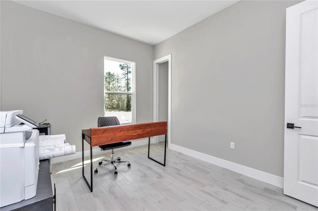 home office with light wood-style floors, baseboards, and washer and clothes dryer