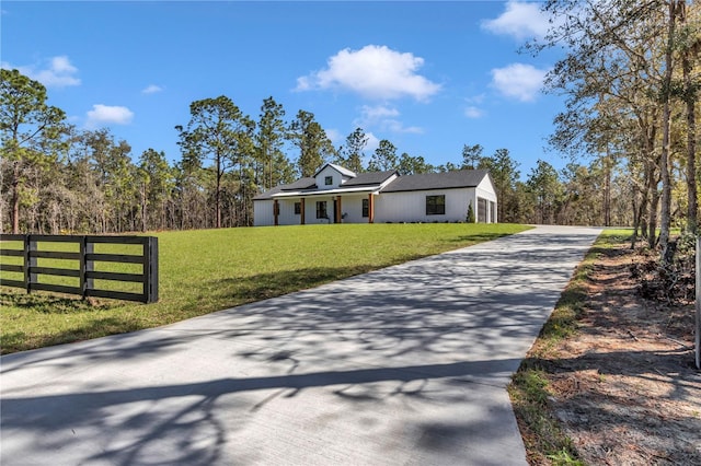 view of front of home with a front yard, concrete driveway, fence, and roof mounted solar panels