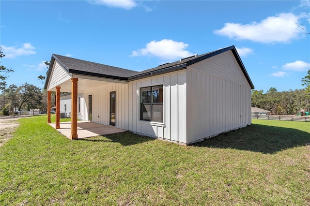 view of property exterior with board and batten siding, a patio area, a yard, and fence