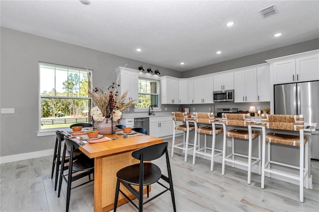 kitchen with stainless steel appliances, a center island, white cabinetry, and a kitchen breakfast bar