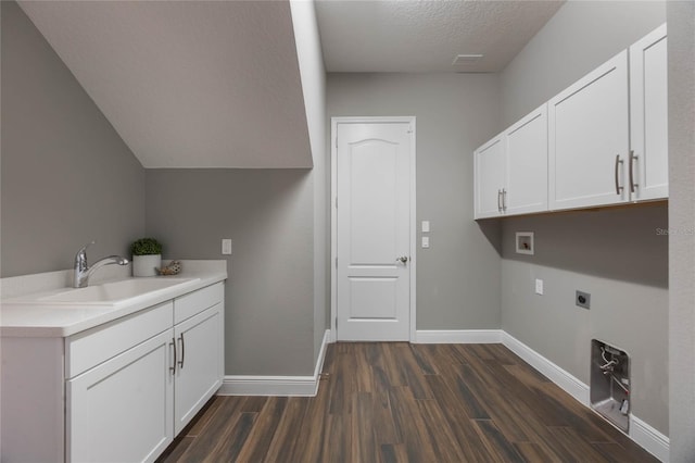 clothes washing area featuring sink, cabinets, hookup for an electric dryer, dark hardwood / wood-style flooring, and a textured ceiling