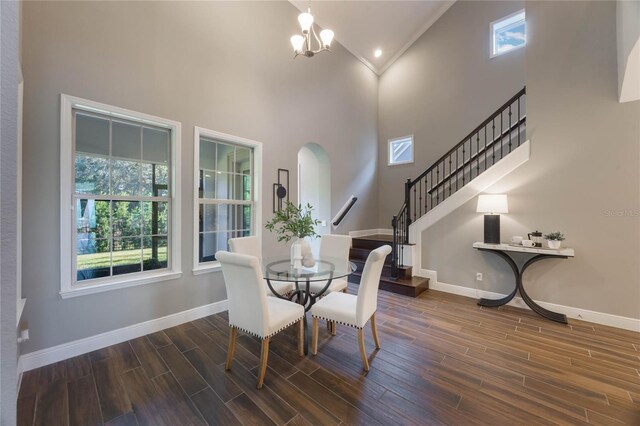 dining room featuring a notable chandelier, dark hardwood / wood-style flooring, crown molding, and high vaulted ceiling