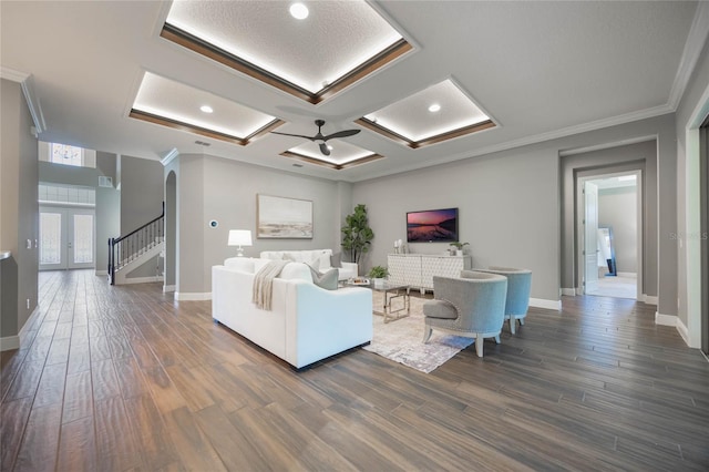 living room featuring dark hardwood / wood-style flooring, ceiling fan, crown molding, and coffered ceiling