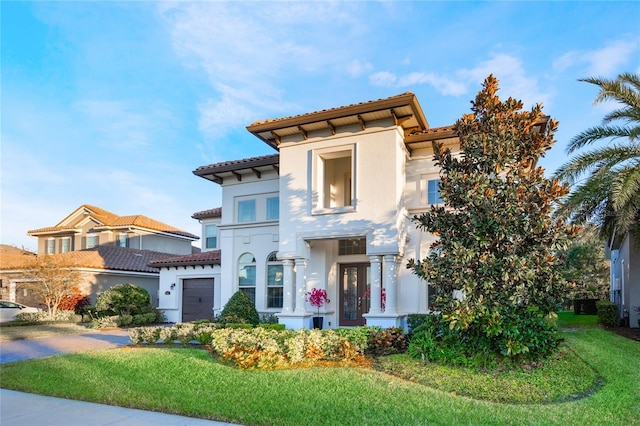 mediterranean / spanish home with a front lawn and a garage