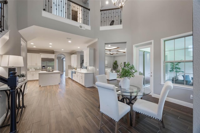 dining room featuring a towering ceiling and dark wood-type flooring