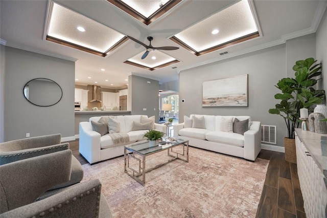 living room featuring coffered ceiling, crown molding, hardwood / wood-style flooring, ceiling fan, and beam ceiling