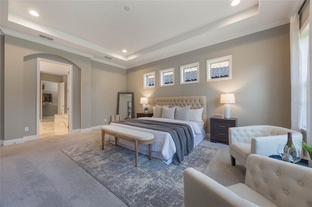 bedroom with light carpet, a tray ceiling, ornamental molding, and ensuite bathroom