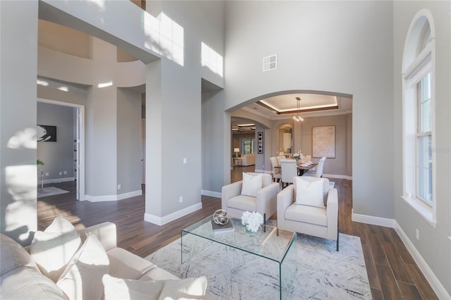 living room with a raised ceiling, plenty of natural light, and dark wood-type flooring