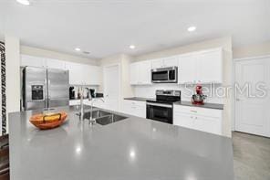 kitchen with stainless steel appliances, white cabinetry, and sink