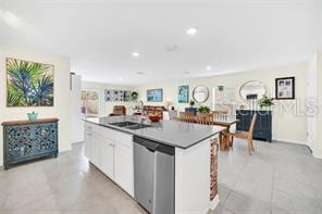 kitchen with white cabinets, sink, dishwasher, and an island with sink