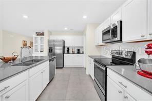 kitchen with white cabinets, sink, light tile patterned floors, and stainless steel appliances