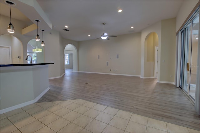 unfurnished living room with sink, ceiling fan, and light tile patterned flooring