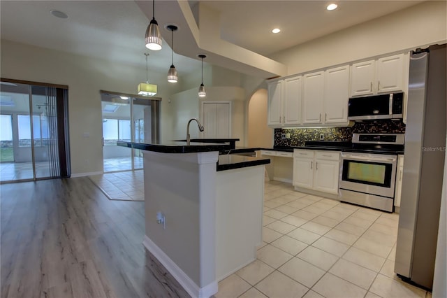 kitchen featuring sink, an island with sink, appliances with stainless steel finishes, decorative light fixtures, and white cabinetry