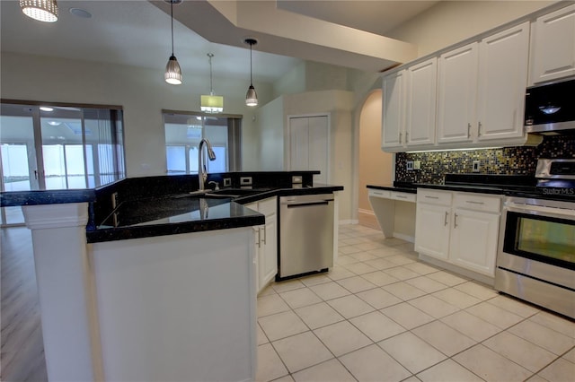 kitchen featuring white cabinets, a center island with sink, sink, appliances with stainless steel finishes, and decorative light fixtures