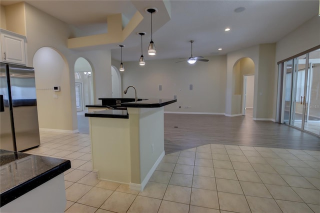 kitchen with sink, ceiling fan, light tile patterned floors, white cabinetry, and stainless steel refrigerator