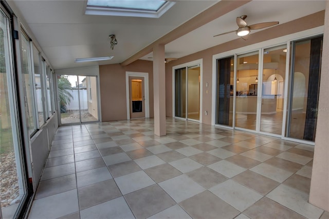 unfurnished sunroom featuring ceiling fan and vaulted ceiling with skylight