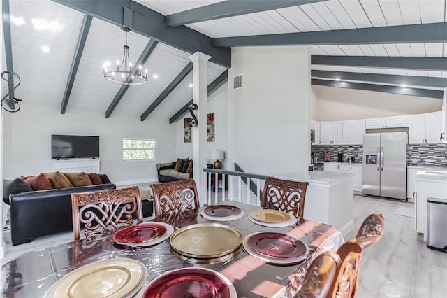 dining room featuring light wood-type flooring, vaulted ceiling with beams, and an inviting chandelier