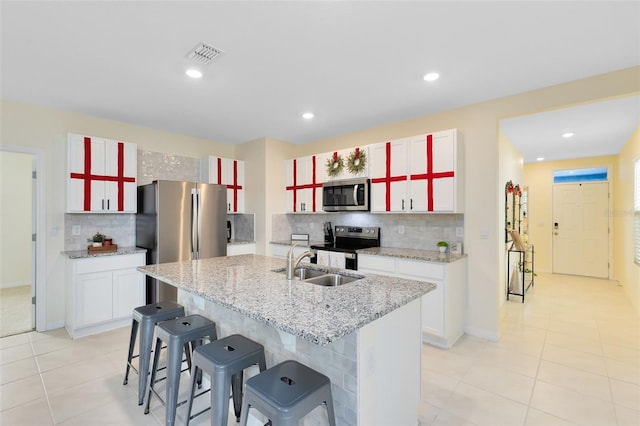 kitchen featuring appliances with stainless steel finishes, tasteful backsplash, white cabinetry, and a kitchen island with sink