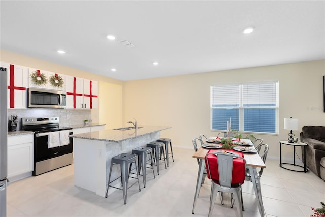 kitchen with backsplash, white cabinets, sink, an island with sink, and appliances with stainless steel finishes