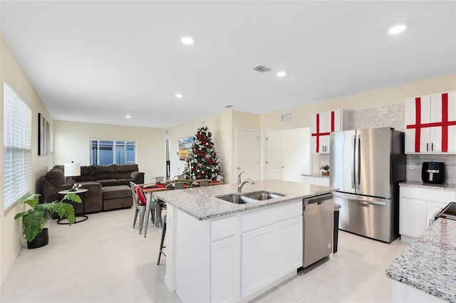 kitchen featuring white cabinetry, sink, backsplash, an island with sink, and appliances with stainless steel finishes