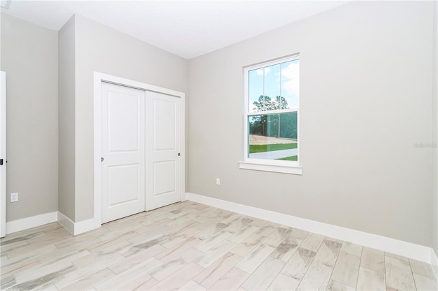 unfurnished bedroom with light hardwood / wood-style flooring and a closet