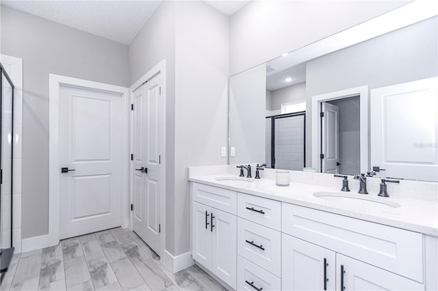 bathroom featuring vanity, an enclosed shower, and a textured ceiling