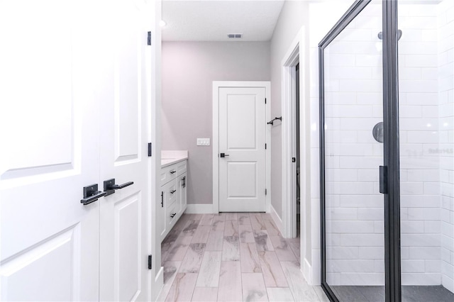 bathroom with hardwood / wood-style floors, vanity, and a shower with door