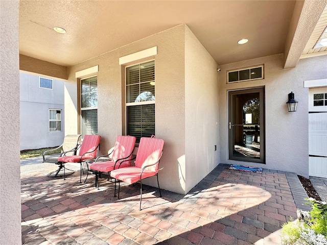 property entrance with stucco siding and a patio