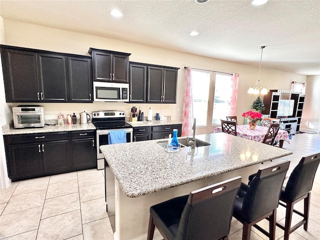 kitchen featuring appliances with stainless steel finishes, a center island with sink, a breakfast bar area, and sink