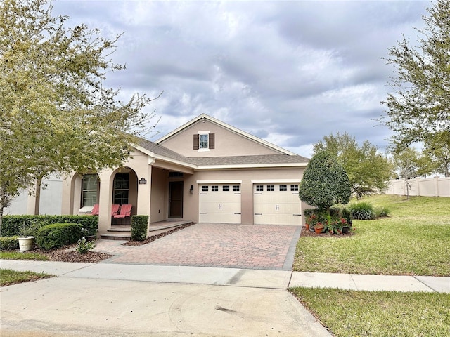 view of front facade with a front yard, stucco siding, covered porch, decorative driveway, and a garage