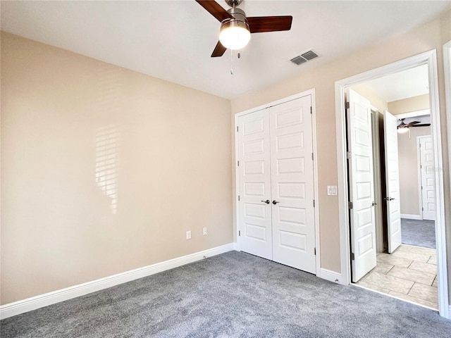 unfurnished bedroom featuring baseboards, visible vents, carpet floors, ceiling fan, and a closet