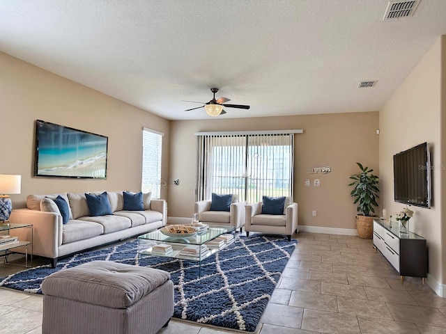 living area featuring visible vents, baseboards, a textured ceiling, and a ceiling fan