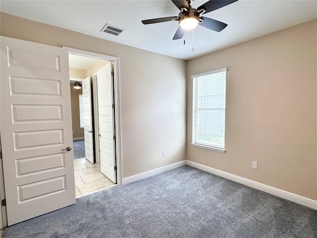 unfurnished bedroom featuring carpet flooring, baseboards, visible vents, and a textured ceiling