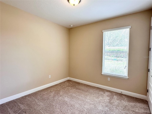 carpeted spare room featuring baseboards